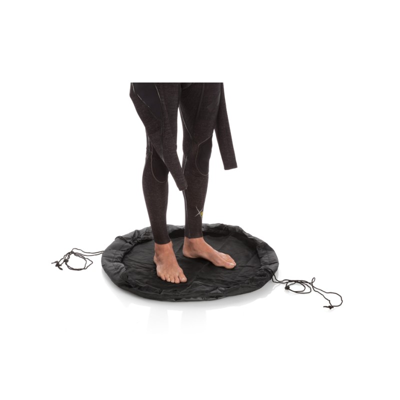 Tapis de change circulaire étanche Surflogic étalé au sol sur un parking, permettant à un surfeur de retirer sa combinaison